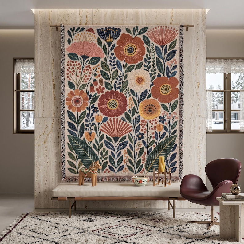 Puede incluir: Un tapiz de pared tejido rectangular que presenta un denso patr&oacute;n bot&aacute;nico de flores y hojas estilizadas en tonos terracota, azul profundo, crema y amarillo mostaza, acabado con un borde de flecos en la parte superior e inferior.