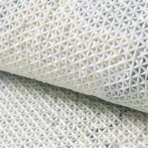 May include: Close-up of a rolled white textured mat. The mat has a repeating pattern of small, raised, star-shaped designs. The texture appears to be made of a flexible material, possibly rubber or a similar substance.