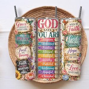 May include: Three cylindrical tumblers with black straws, featuring colorful floral patterns and religious text. The designs include phrases like Grace Changes Everything, God Says You Are Forgiven, and Walk By Faith, decorated with butterflies and hearts.