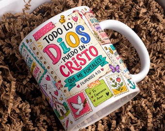 May include: A white ceramic mug featuring a colorful collage of stamps and notes with the Spanish text Todo lo puedo en Cristo que me fortalece Filipenses 4:13, alongside illustrations of a white dove, a church, a butterfly, and floral motifs.