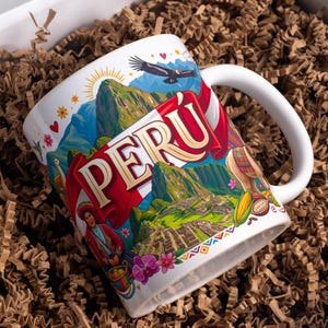 Puede incluir: Una taza de cerámica blanca con una ilustración colorida de Machu Picchu, la bandera peruana, un cóndor, una llama y una persona con vestimenta tradicional. La palabra PERÚ está impresa en letras grandes y llamativas con borde dorado.