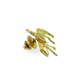 May include: A gold-toned pin featuring a horse and rider. The pin has a safety clasp on the back.