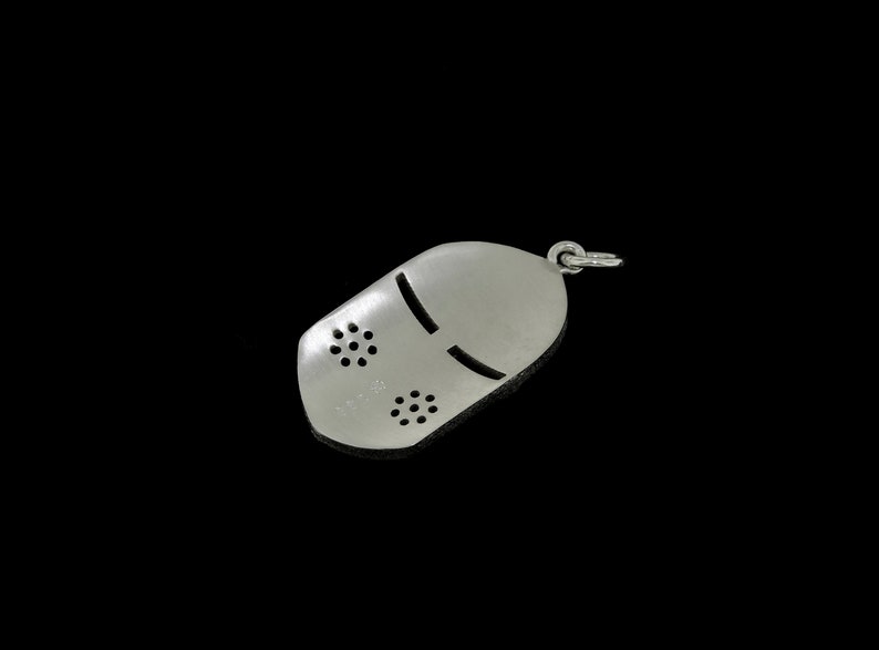 May include: Silver charm in the shape of a knight's helmet with a face mask design. The helmet has a small loop at the top for attaching to a chain or bracelet.