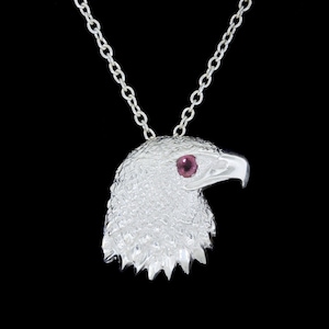 May include: Silver eagle head pendant necklace with a red gemstone eye.