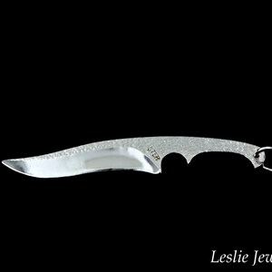 May include: A silver knife with a textured blade and a small ring on the handle. The knife is about 6 inches long.