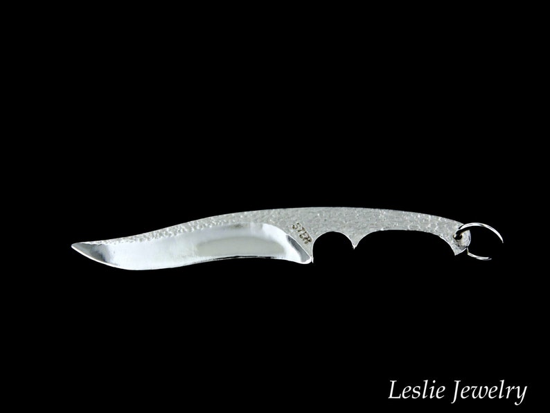 May include: A silver knife with a textured blade and a small ring on the handle. The knife is about 6 inches long.