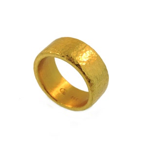 May include: A gold hammered band ring. The ring is thick and has a textured surface.