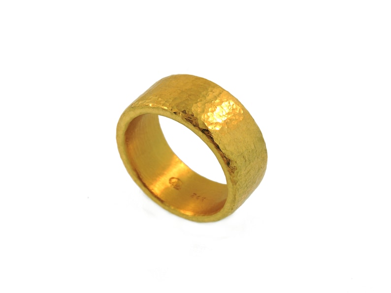 May include: A gold hammered band ring. The ring is thick and has a textured surface.