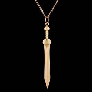 May include: A gold-toned necklace with a sword pendant. The sword has a rounded tip and a detailed handle.