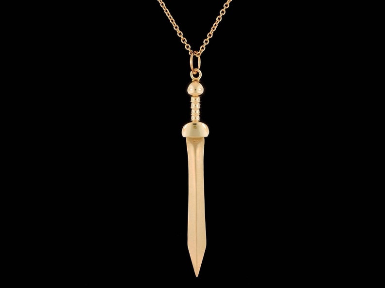 May include: A gold-toned necklace with a sword pendant. The sword has a rounded tip and a detailed handle.