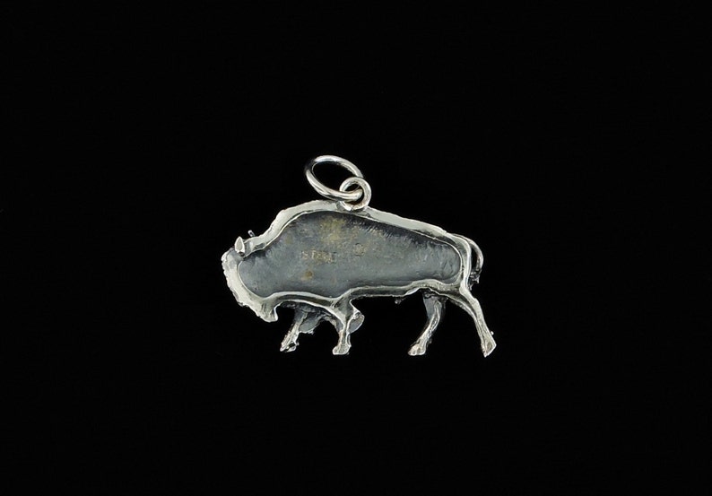 May include: Silver charm in the shape of a buffalo, with a loop for attaching to a necklace or bracelet.