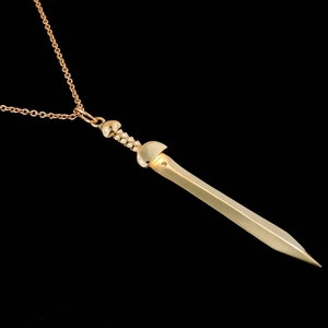 May include: A gold-toned necklace with a sword pendant. The sword has a detailed hilt and a sharp point.