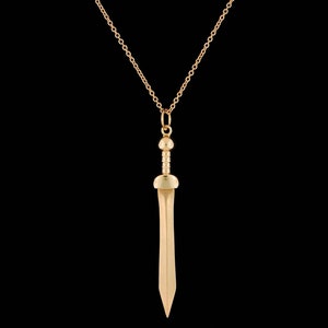 May include: A gold chain necklace with a gold sword pendant. The sword has a rounded tip and a detailed handle.