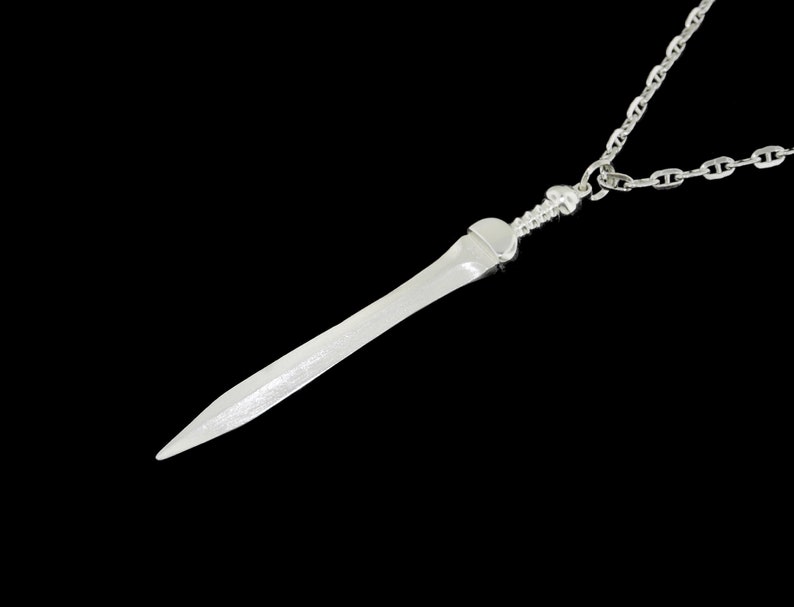 May include: A silver sword pendant necklace with a chain link design. The pendant is a detailed replica of a sword with a pointed tip.