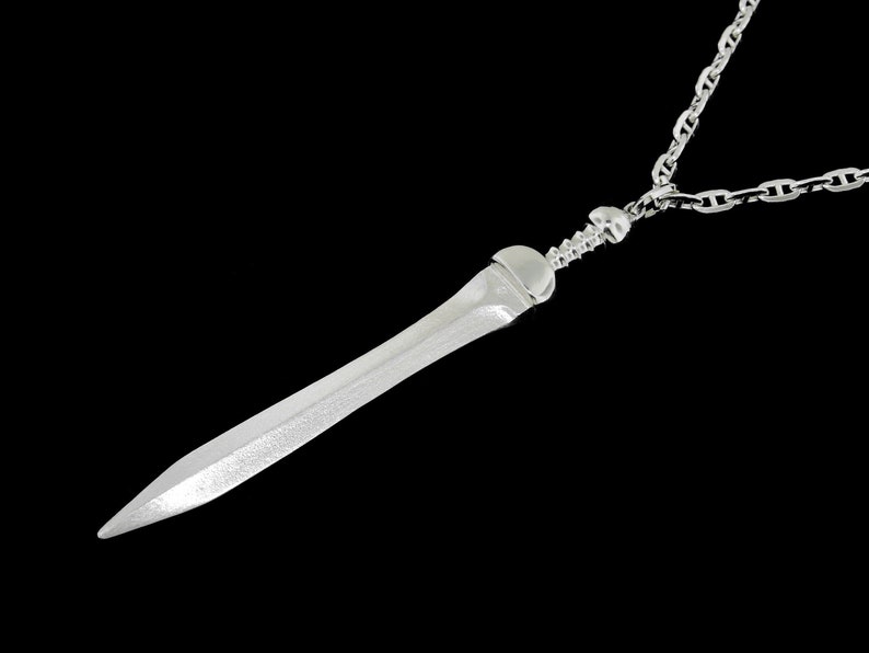May include: A silver necklace with a sword pendant. The sword is detailed and has a sharp point.