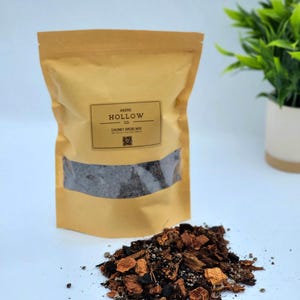 May include: A brown paper bag of "Chunky Aroid Mix" soil mix with a clear window, and a pile of the mix in front. The bag has the text "AKERS HOLLOW CO." and a small plant is in the background.