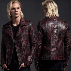Peut inclure: Veste en cuir bordeaux et noir avec un motif peau de serpent. La veste présente un style motard classique avec un col cranté, une fermeture éclair asymétrique et plusieurs poches. Le dos de la veste a un motif à panneaux verticaux.