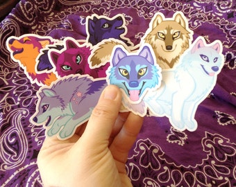 May include: A set of seven wolf stickers featuring different colored fur and expressions. The stickers are printed on white paper and have a glossy finish.