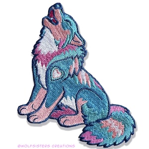 Könnte beinhalten: Ein gestickter Aufnäher mit einem blauen, rosa und weißen Wolf, der zum Mond heult. Der Wolf hat ein Herz auf der Brust und einen buschigen Schwanz.