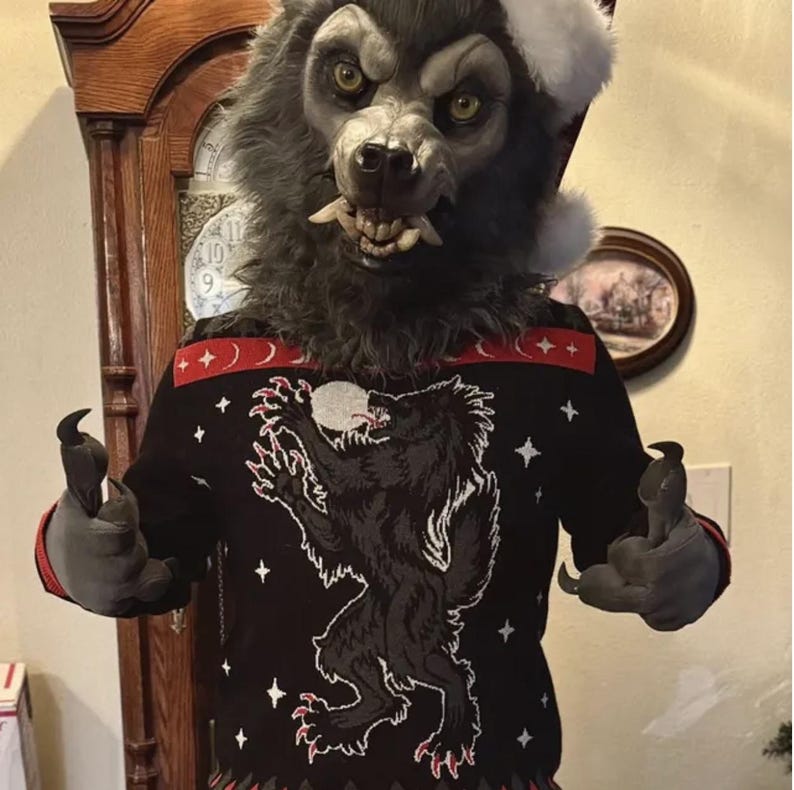 May include: A werewolf wearing a black and red Christmas sweater with a werewolf howling at the moon design. The sweater has a white snowflake pattern and red trim. The werewolf is wearing a Santa hat.