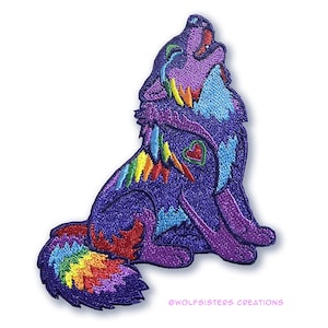Può includere: Una toppa ricamata colorata di un lupo che ulula con un design arcobaleno e un piccolo cuore rosso sul petto. La toppa è bordata di nero e ha uno sfondo viola. Il testo "@WOLFSISTERS CREATIONS" è nella parte inferiore della toppa.