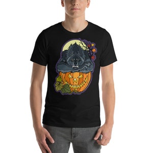 May include: A black t-shirt with a graphic of a werewolf inside a jack-o'-lantern. The werewolf is snarling and has a full moon behind it.