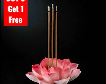 May include: A pink and white lotus flower incense holder with three thin brown incense sticks standing upright in the center. A red rectangular box in the upper left corner contains the white text BUY 3 Get 1 Free against a black background.