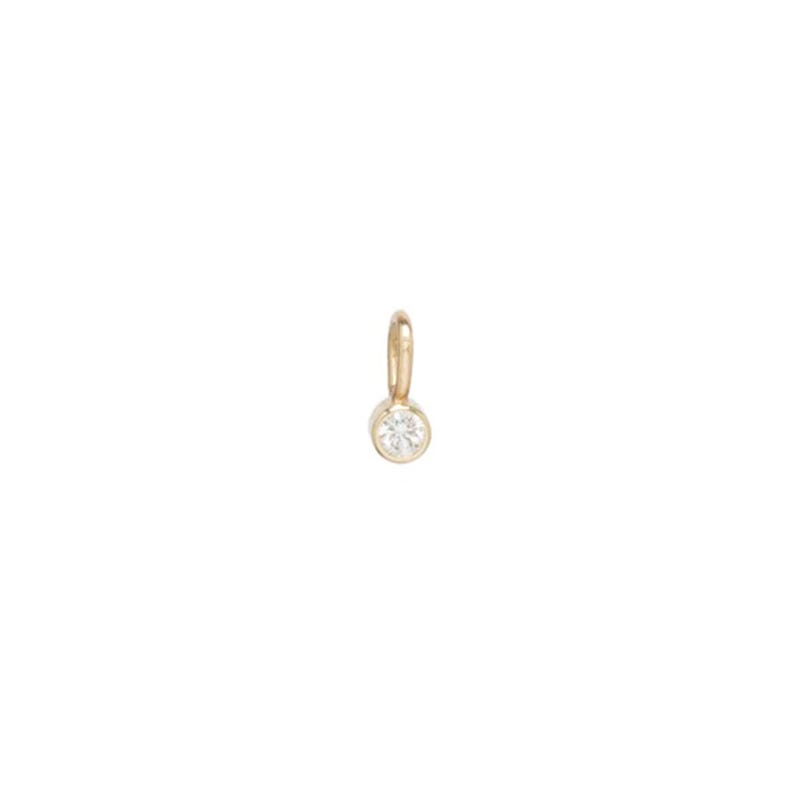 May include: A small, gold-colored pendant with a single, round, clear gemstone. The gemstone is set in a bezel setting. The pendant has a small loop at the top for attaching to a chain or bracelet.
