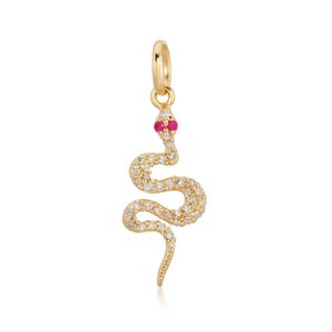 Puede incluir: Colgante de serpiente dorado con un lazo en la parte superior. La serpiente está incrustada con pequeñas piedras transparentes y tiene dos piedras rojas para los ojos. El cuerpo de la serpiente se curva.