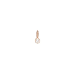 May include: A small, rose gold pendant with a single, round, clear gemstone. The pendant has a simple design with a loop at the top for attaching to a chain or bracelet. The gemstone is set in a bezel setting.