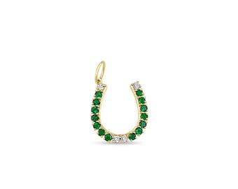 May include: A gold horseshoe pendant adorned with green and white gemstones. The horseshoe shape is a classic symbol of luck, with the gemstones adding a touch of elegance. The pendant is designed to be worn as a necklace.