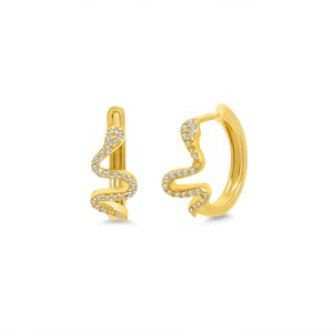 Puede incluir: Un par de pendientes de aro dorados con forma de serpiente. El diseño de la serpiente está adornado con pequeñas piedras preciosas transparentes. Los pendientes se muestran sobre un fondo blanco.