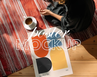 Könnte beinhalten: Ein Poster-Mockup mit minimalistischem Kunstdesign mit orangefarbenen, blauen, gelben und schwarzen geometrischen Formen. Das Poster befindet sich auf einer Holzoberfläche mit einem rot-weiß gestreiften Teppich und einer Tasse Kaffee.