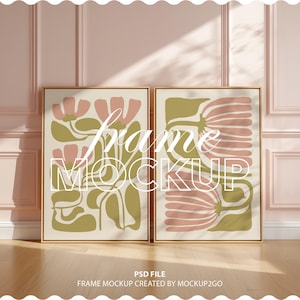 Könnte beinhalten: Zwei gerahmte Kunstdrucke mit floralen Designs in Rosa und Olivgrün. Die Rahmen sind goldfarben und die Kunstwerke werden vor einem hellen Hintergrund präsentiert. Der Text "frame MOCKUP" ist auf das Kunstwerk gelegt. Der untere Teil des Bildes lautet "PSD FILE FRAME MOCKUP CREATED BY MOCKUP2GO."