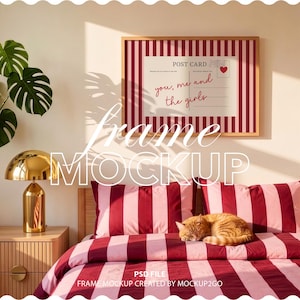 May include: A framed postcard print with a red and white striped background, featuring the text "you, me and the girls" and a heart. The frame is displayed above a bed with matching red and pink striped bedding. A golden lamp and a sleeping orange cat are also visible.