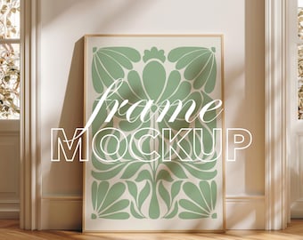 May include: A framed art print mockup with a light green floral design on a cream background. The words "frame MOCKUP" are overlaid in white. The frame is a light wood colour, and the image is displayed in a room setting.