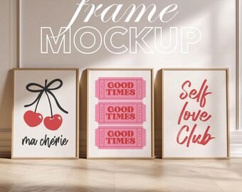May include: Three framed art prints with a light wood finish. The prints feature a cherry design with the text "ma chérie", pink ticket stubs with "GOOD TIMES", and the words "Self love Club" in red. The image is a frame mockup.