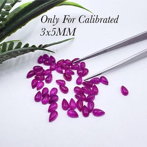 May include: A collection of small, pear-shaped, vibrant magenta gemstones scattered on a white surface. Metal tweezers are positioned near the stones. Text in the image reads: Only For Calibrated 3x5MM. The stones have a faceted, reflective surface.