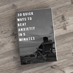 Könnte beinhalten: Ein schwarz-weißes Buchcover mit dem Titel "30 Quick Ways to Beat Anxiety in 5 Minutes". Das Bild zeigt eine Person, die in einem Holzstuhl sitzt und aufs Meer blickt. Das Buch liegt auf einer Holzoberfläche.