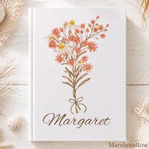 Puede incluir: Un diario blanco con un diseño floral de flores naranjas y blancas, tallos marrones y el nombre "Margaret" en escritura marrón. La palabra "Marshmallow" está en la esquina inferior derecha.