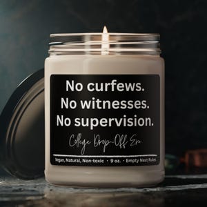 May include: A lit candle in a glass jar with a black label. The label reads "No curfews. No witnesses. No supervision. College Drop-Off Era." The candle is 9 oz and is vegan, natural, and non-toxic.