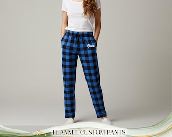 May include: Blue and black plaid flannel custom pants with a drawstring waist and pockets. The word "Dove" is printed in white on the left leg. The text "FLANNEL CUSTOM PANTS" is at the bottom of the image.