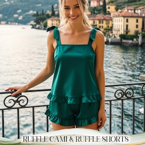 May include: Emerald green cami top and ruffle shorts set. The top has tie straps and the shorts have a ruffled hem. The text "RUFFLE CAMI & RUFFLE SHORTS" is at the bottom of the image. The set is made of a silky material.