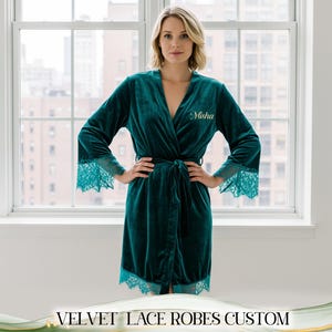May include: A teal velvet robe with lace trim on the sleeves and hem. The robe has a wrap-around design with a matching belt. The name "Misha" is embroidered on the chest. The text "VELVET LACE ROBES CUSTOM" is at the bottom.