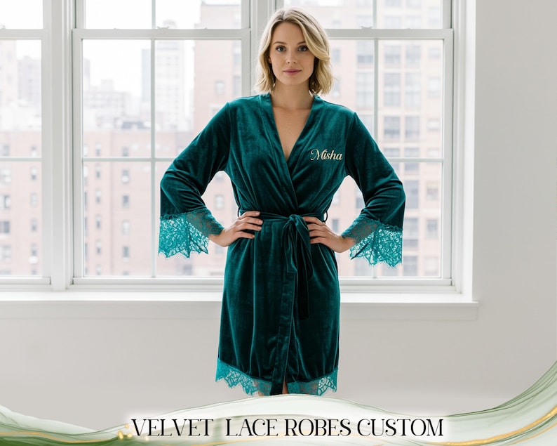 May include: A teal velvet robe with lace trim on the sleeves and hem. The robe has a wrap-around design with a matching belt. The name "Misha" is embroidered on the chest. The text "VELVET LACE ROBES CUSTOM" is at the bottom.