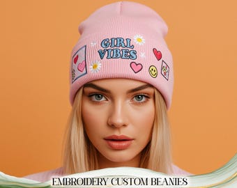 May include: A light pink beanie with the words "GIRL VIBES" embroidered on the front, along with various patches including a heart, a daisy, and a smiley face. The beanie is a stylish accessory.