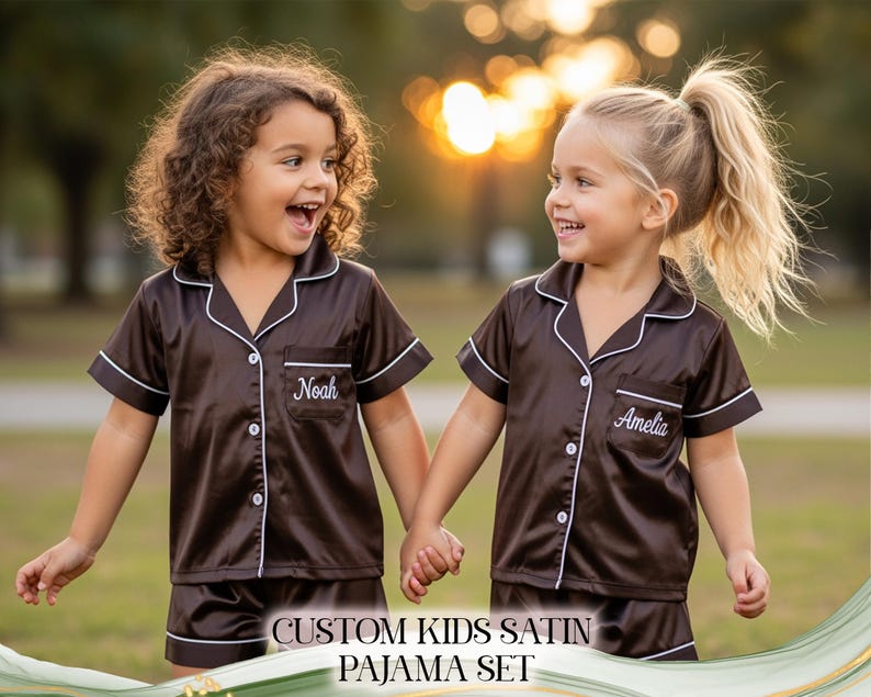 Puede incluir: Dos ni&ntilde;os con conjuntos de pijama de sat&eacute;n marr&oacute;n a juego con ribetes blancos y nombres personalizados. Los conjuntos de pijama incluyen una camisa con botones y pantalones cortos. El texto "CUSTOM KIDS SATIN PAJAMA SET" est&aacute; en la parte inferior de la imagen.