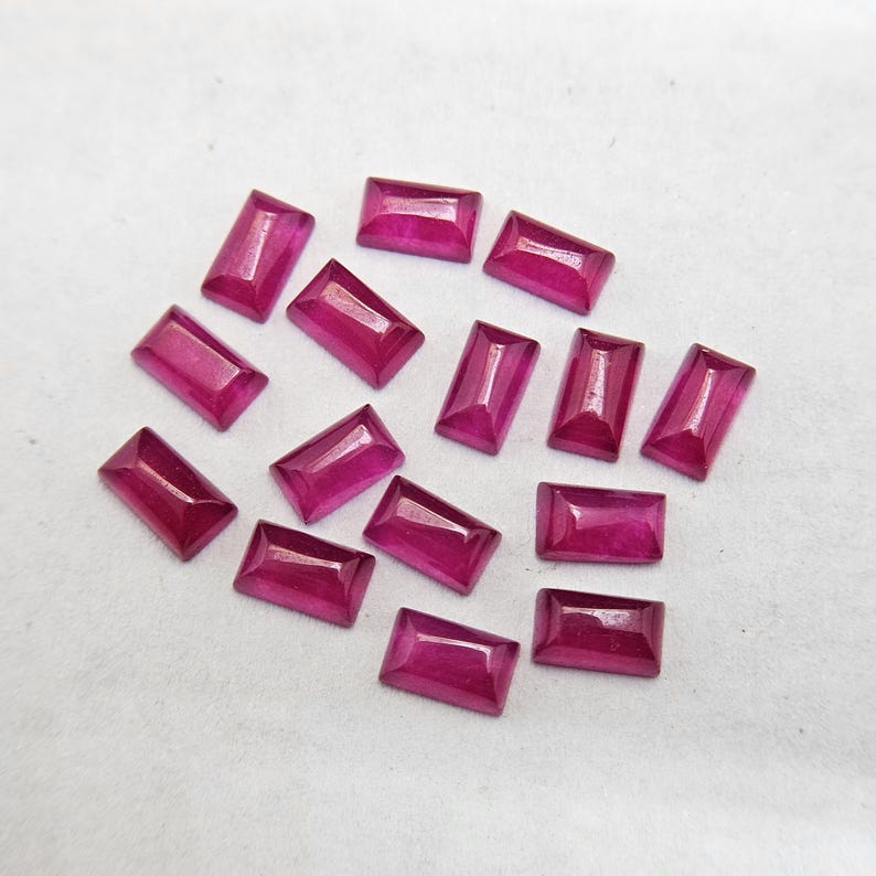 Pode incluir: Uma cole&ccedil;&atilde;o de pedras preciosas retangulares, magenta profundo. As gemas s&atilde;o facetadas, com uma superf&iacute;cie polida, e est&atilde;o dispostas sobre um fundo branco. As pedras t&ecirc;m uma cor rica e saturada.
