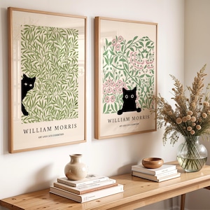 May include: Two framed art prints featuring William Morris designs with black cat silhouettes. One print has green foliage, the other pink flowers. The text "WILLIAM MORRIS ART AND CATS EXHIBITION" is below the images.
