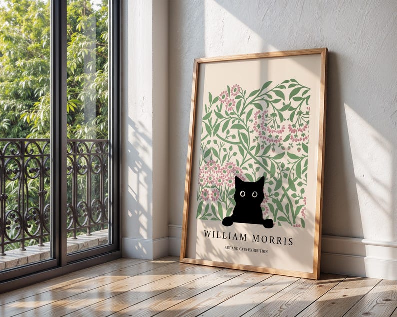 May include: A framed art print featuring a black cat peeking out from a floral design with pink and green accents. The print includes the text "WILLIAM MORRIS ART AND CATS EXHIBITION" in a wooden frame.
